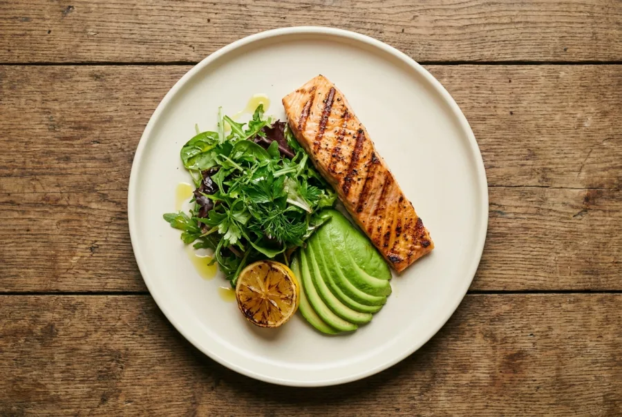 Bord met gegrilde zalm, salade en avocado